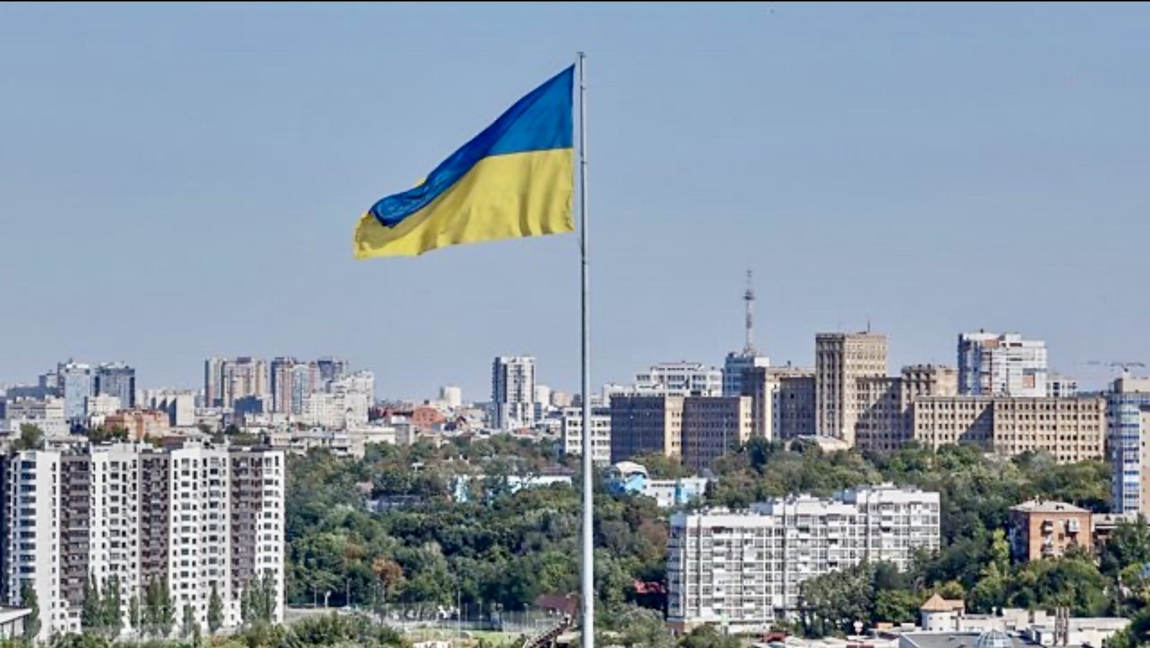 Ukrainian flag flying over a city skyline marking the anniversary of Russia’s full-scale invasion of Ukraine