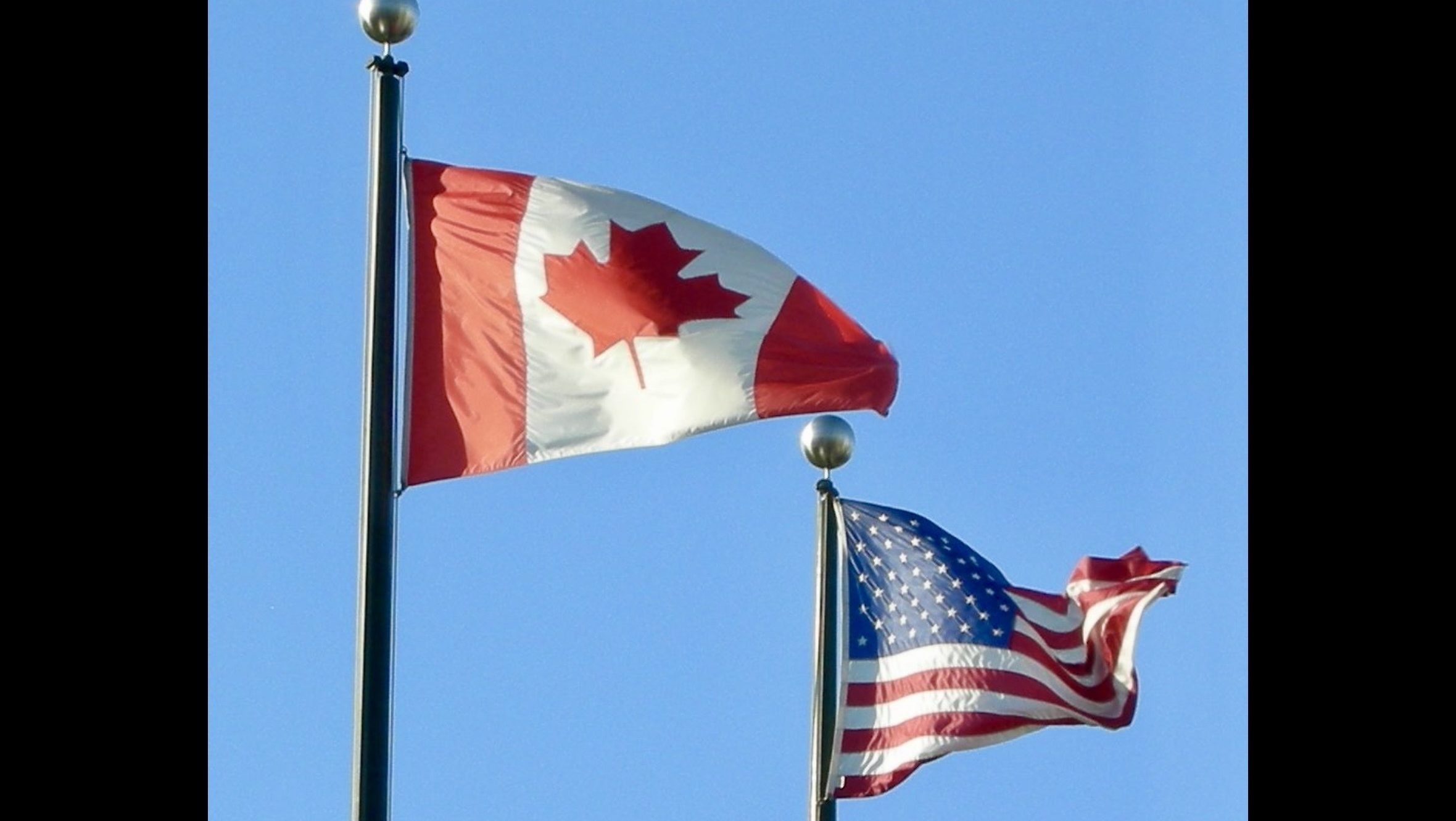 Canadian and United States flags displayed at the Peace Arch border crossing, symbolizing cross-border trade and diplomatic relations between the two countries.