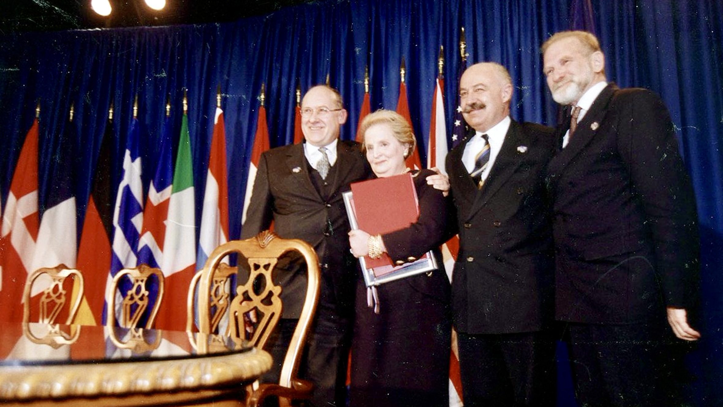 Poland NATO accession ceremony 1999 with officials standing in front of alliance member flags