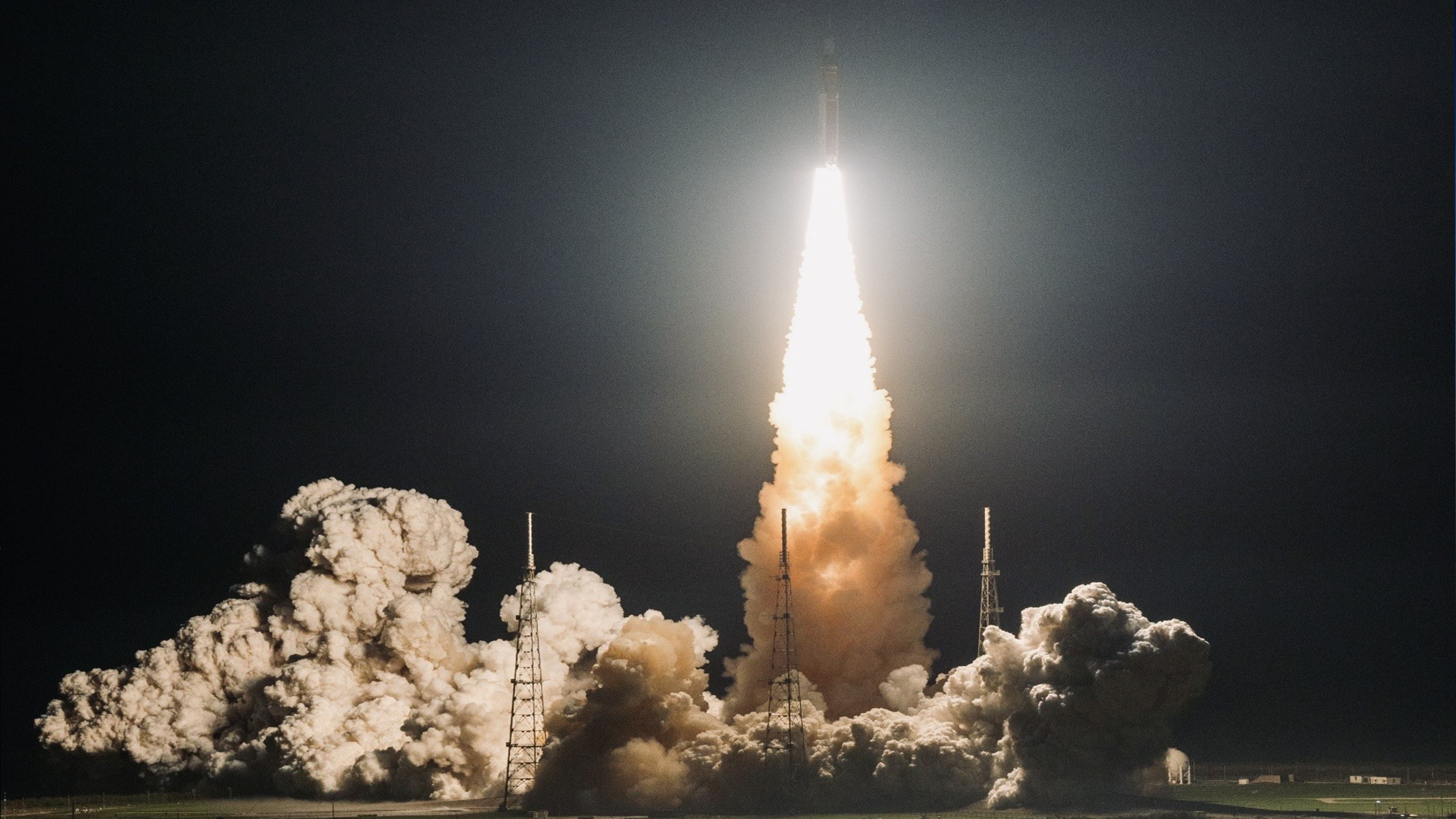 NASA’s Space Launch System (SLS) rocket launches at night, with a bright plume of fire and smoke illuminating the launch pad during an Artemis mission