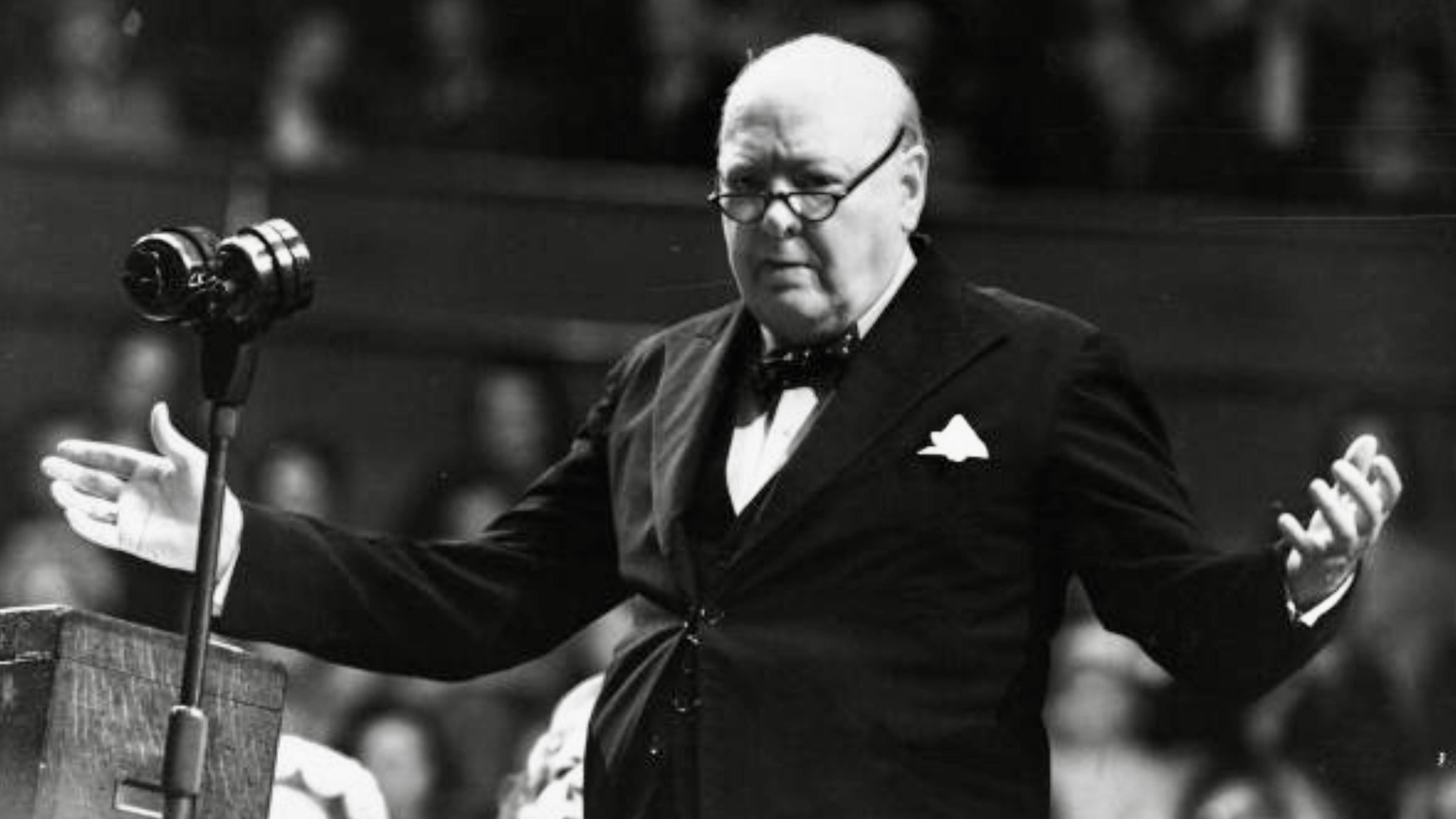 British Prime Minister Winston Churchill speaking at a podium during World War II.