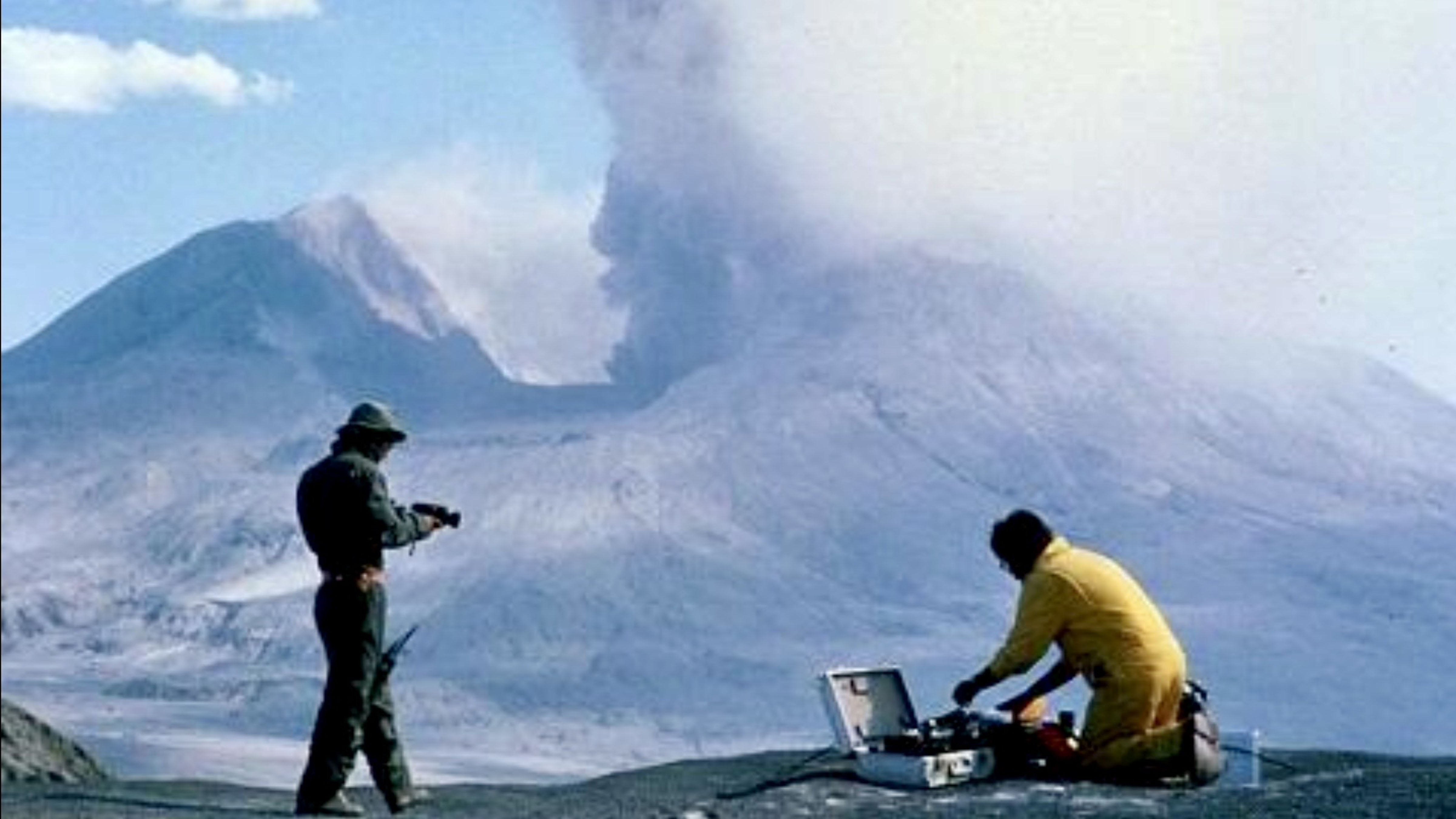 Scientists monitor volcanic activity near Mount St. Helens during the 1980 eruption in Washington State as ash rises from the crater.