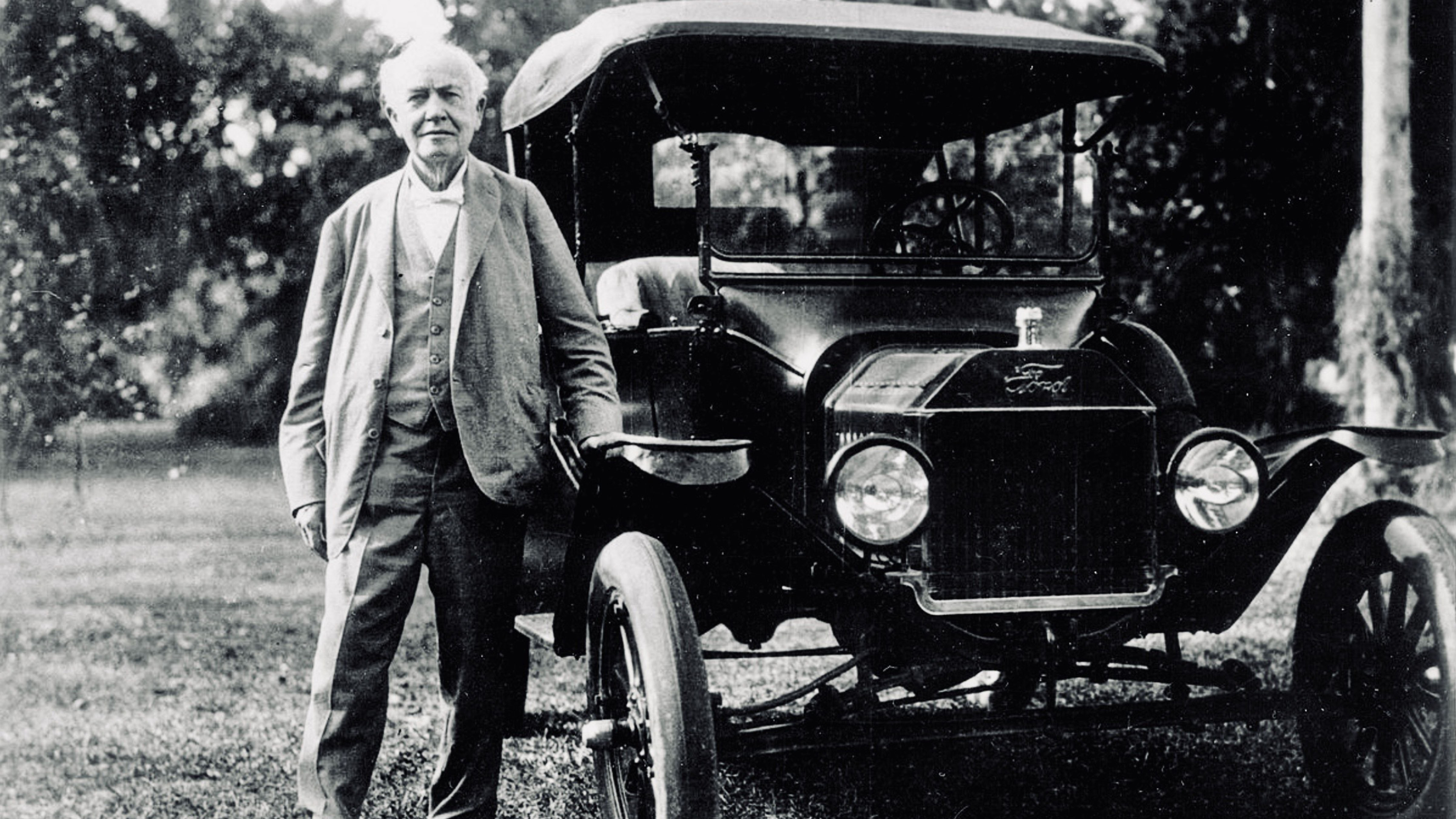 Henry Ford standing beside an early Ford automobile during the formative years of Ford Motor Company.