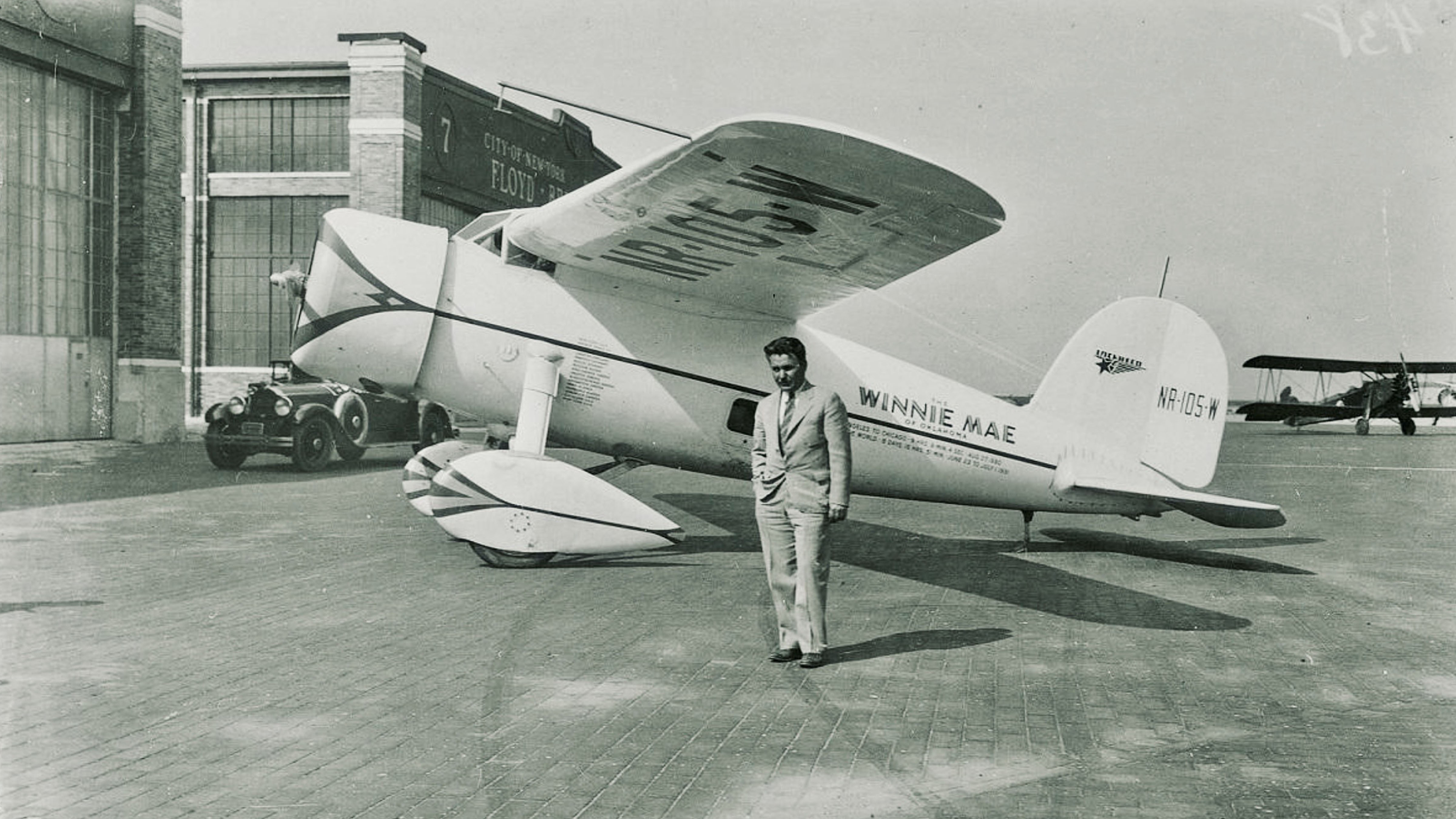 Aviator Wiley Post stands beside the Lockheed Vega Winnie Mae, the aircraft he flew to become the first person to fly solo around the world in 1933.